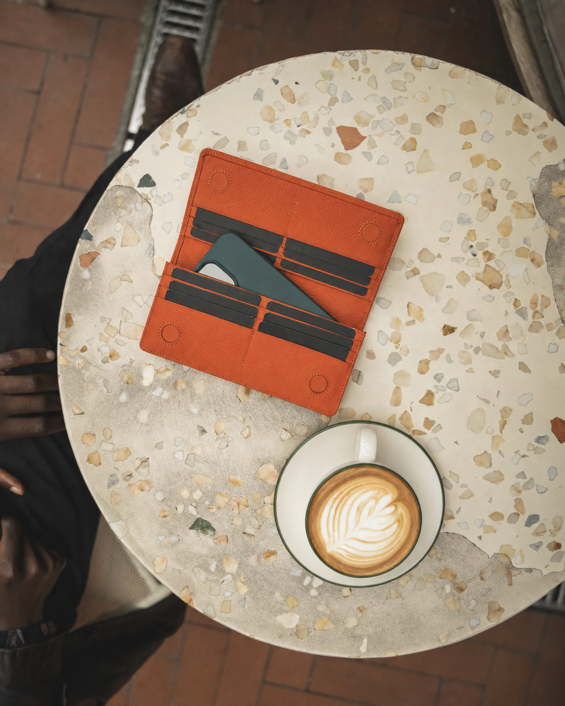 Turuncu cüzdan kafe masasında açık halde, telefon kart bölmelerinin yanında